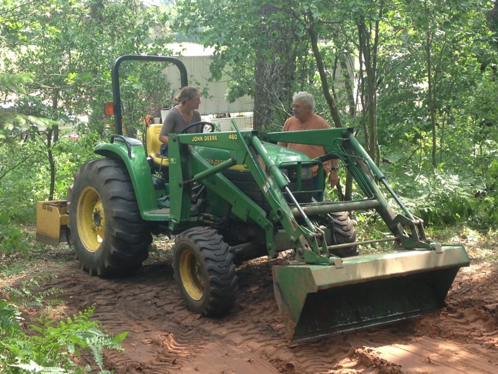 Neighbor Dave teaching Kristin how to dig a root cellar hole with his tractor